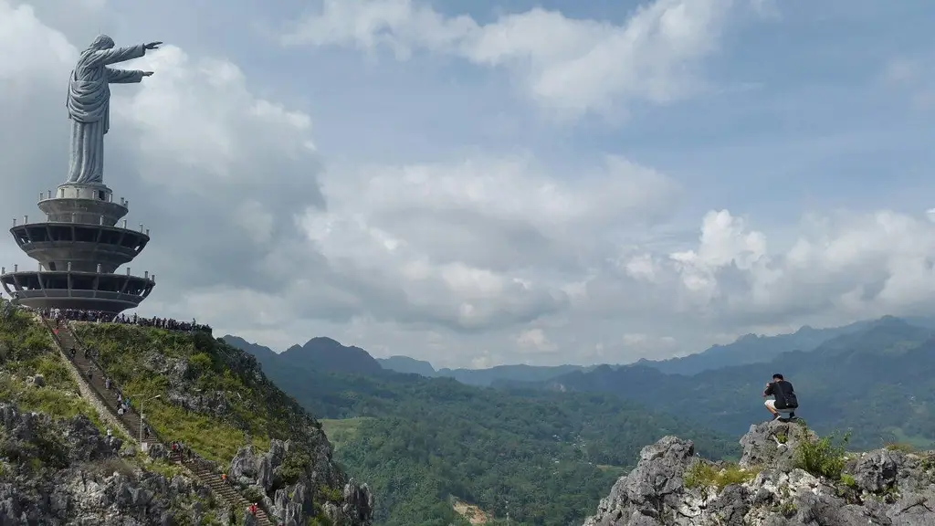 A figure on a rocky ridge above forested mountains