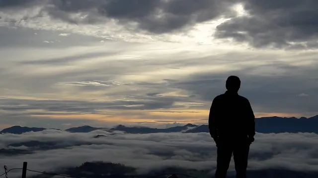 A figure silhouetted against cloud and dawn light at Lolai